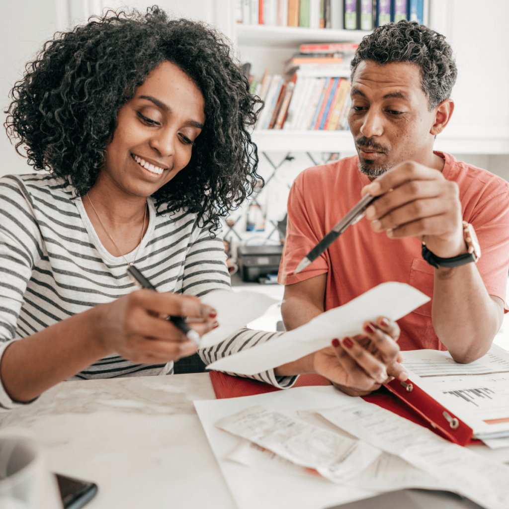 A man and a woman are sitting at a table looking at papers.